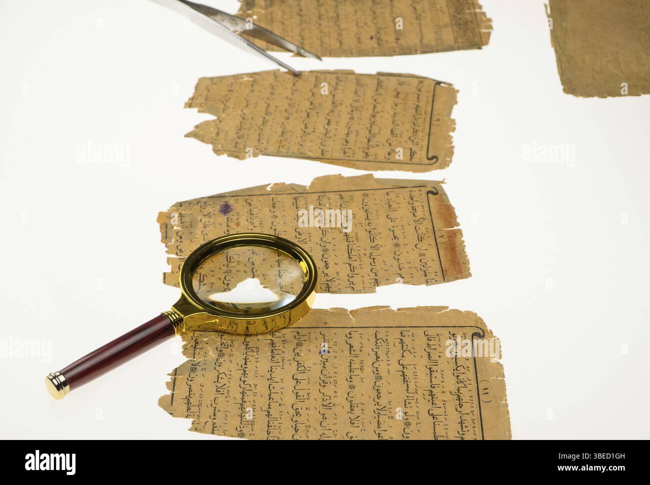 Livre pages avec un manuscrit arabe sur une table avec une lumière et une loupe. Paléographie, l'étude de l'écriture arabe ancienne Banque D'Images