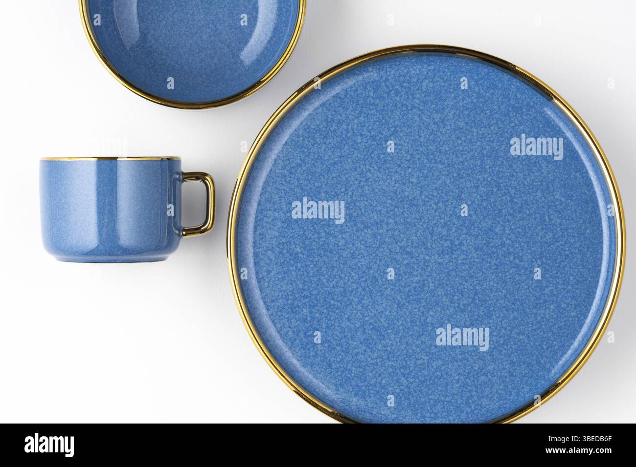Un ensemble d'assiettes en céramique bleue et une tasse sur un fond blanc. Vue de dessus Banque D'Images
