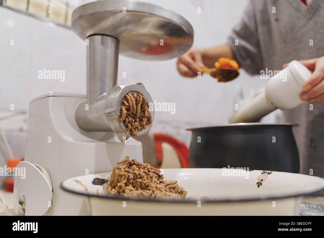 Hachoir à viande dans la cuisine à la maison. Photographie de style de vie. Préparation des aliments . Banque D'Images