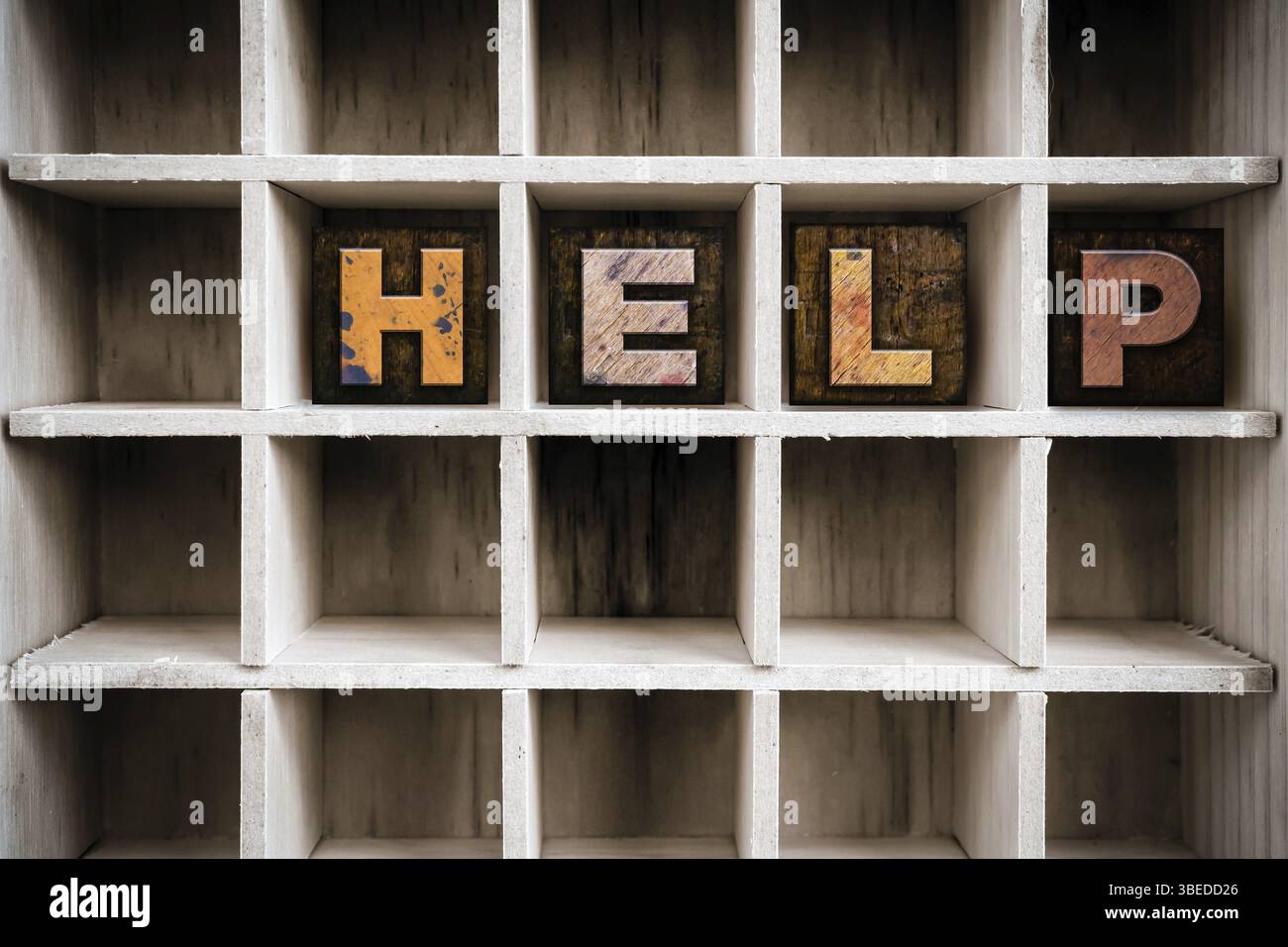 Le mot HELP écrit en typographie en bois taché à l'encre vintage dans un tiroir d'imprimante cloisonné Banque D'Images