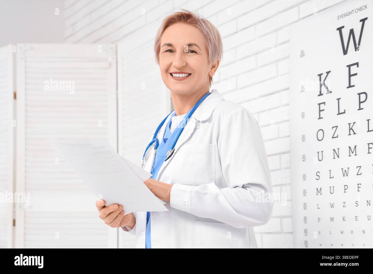 Heureux médecin féminin mature avec stéthoscope et documents en clinique Banque D'Images