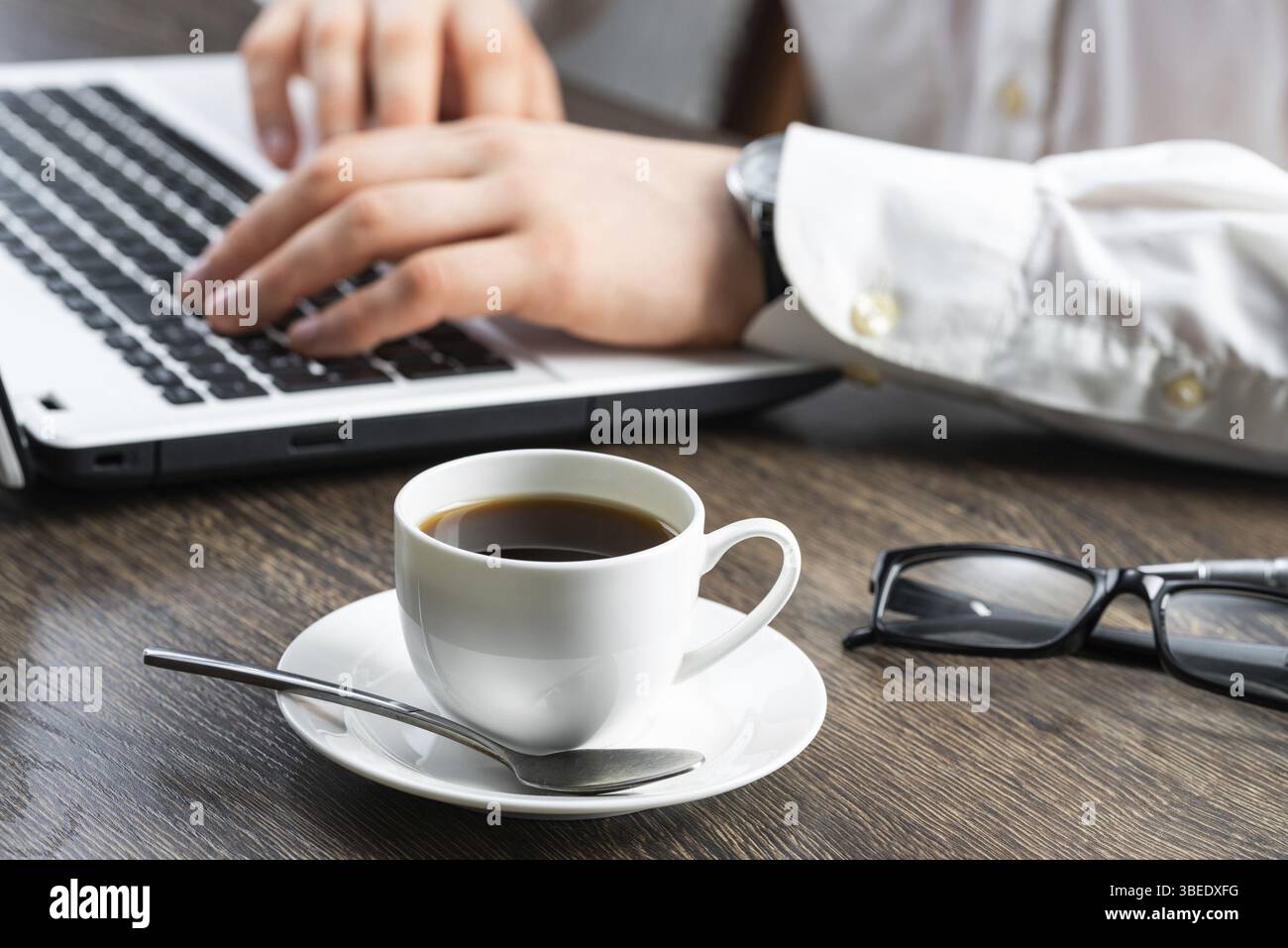 Homme d'affaires assis au bureau et utilisant un ordinateur portable. Gros plan sur les mains de l'homme tapant sur le clavier au bureau. Espace de consultation avec vue latérale avec lunettes et Banque D'Images