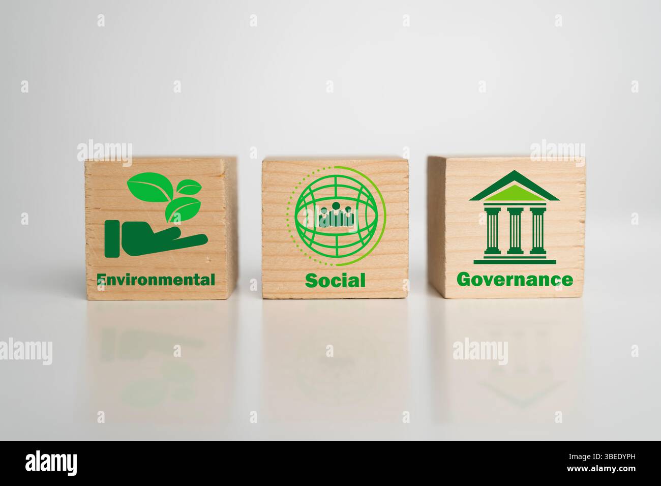 Trois blocs de bois avec des icônes vertes symbolisent les principes ESG : environnemental, social et gouvernance, représentant la durabilité de l'entreprise et le respon Banque D'Images