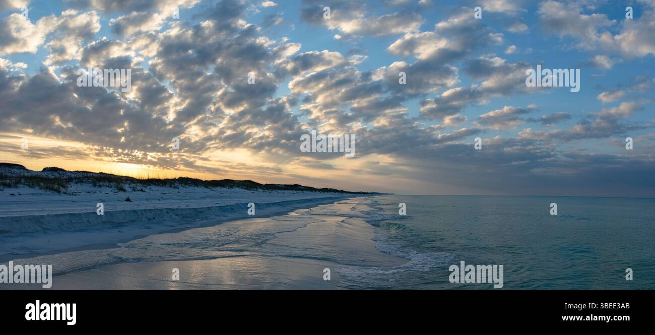 Motif de nuages étonnant au lever du soleil au-dessus de la plage de sable blanc et des dunes de sable du parc d'État Top Sail Hill à destin Floride. Banque D'Images