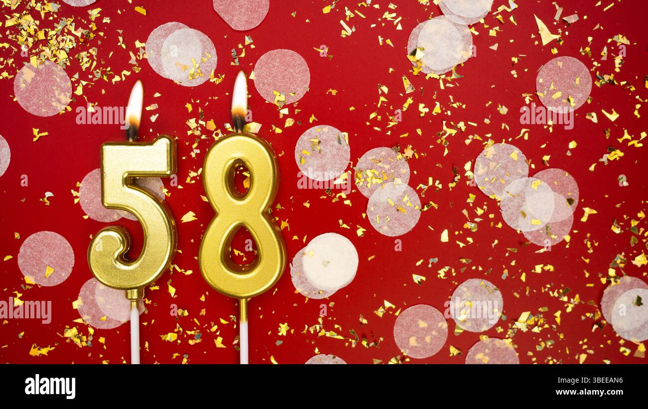 Numéro de bougie brûlante dorée chiffre cinquante-huit. Carte de voeux d'anniversaire avec inscription 58 sur fond rouge avec confettis et paillettes. Anniversaire, c Banque D'Images