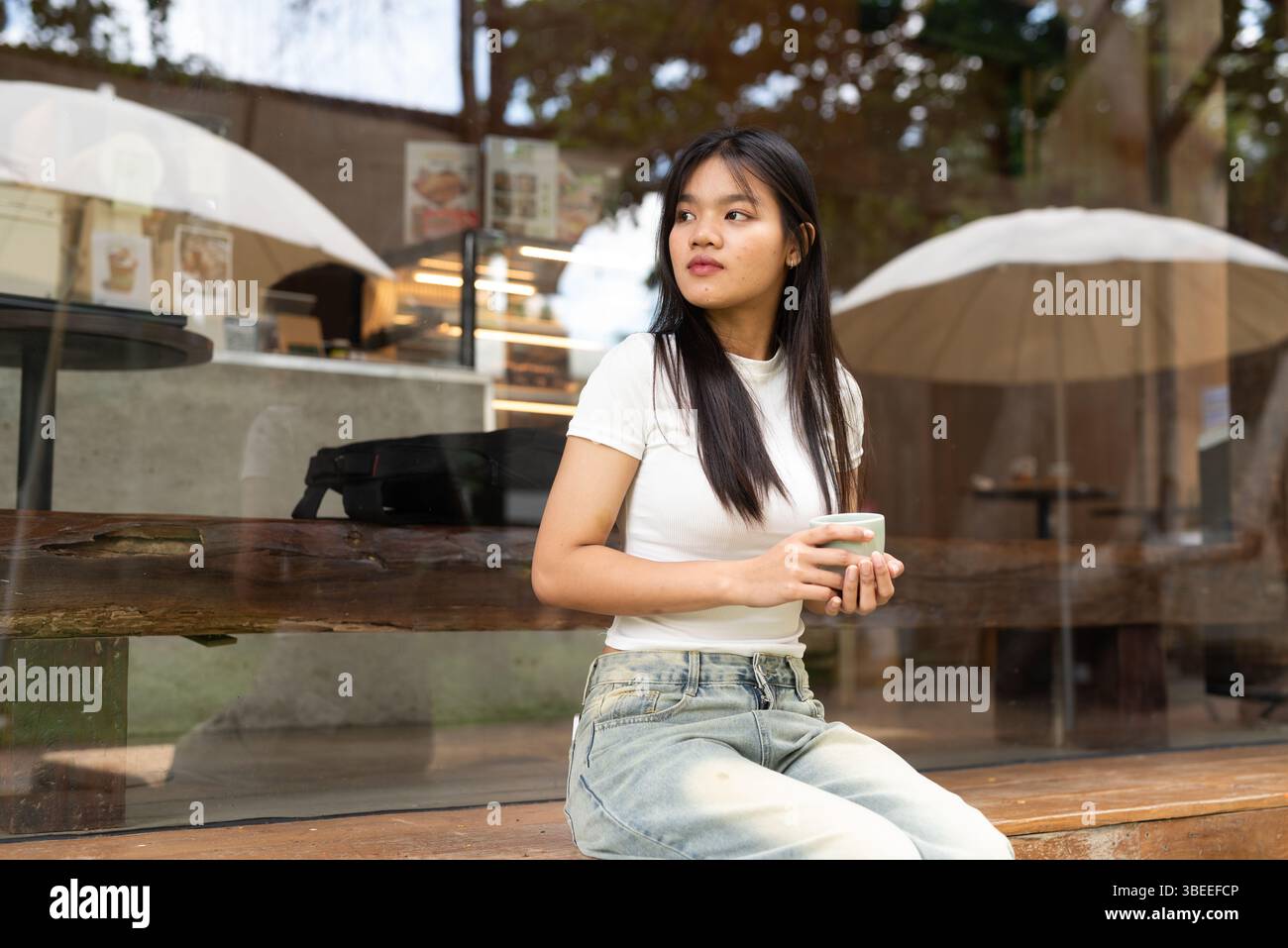 Jeune belle femme asiatique se relaxant à l'extérieur du café dans la ville Banque D'Images