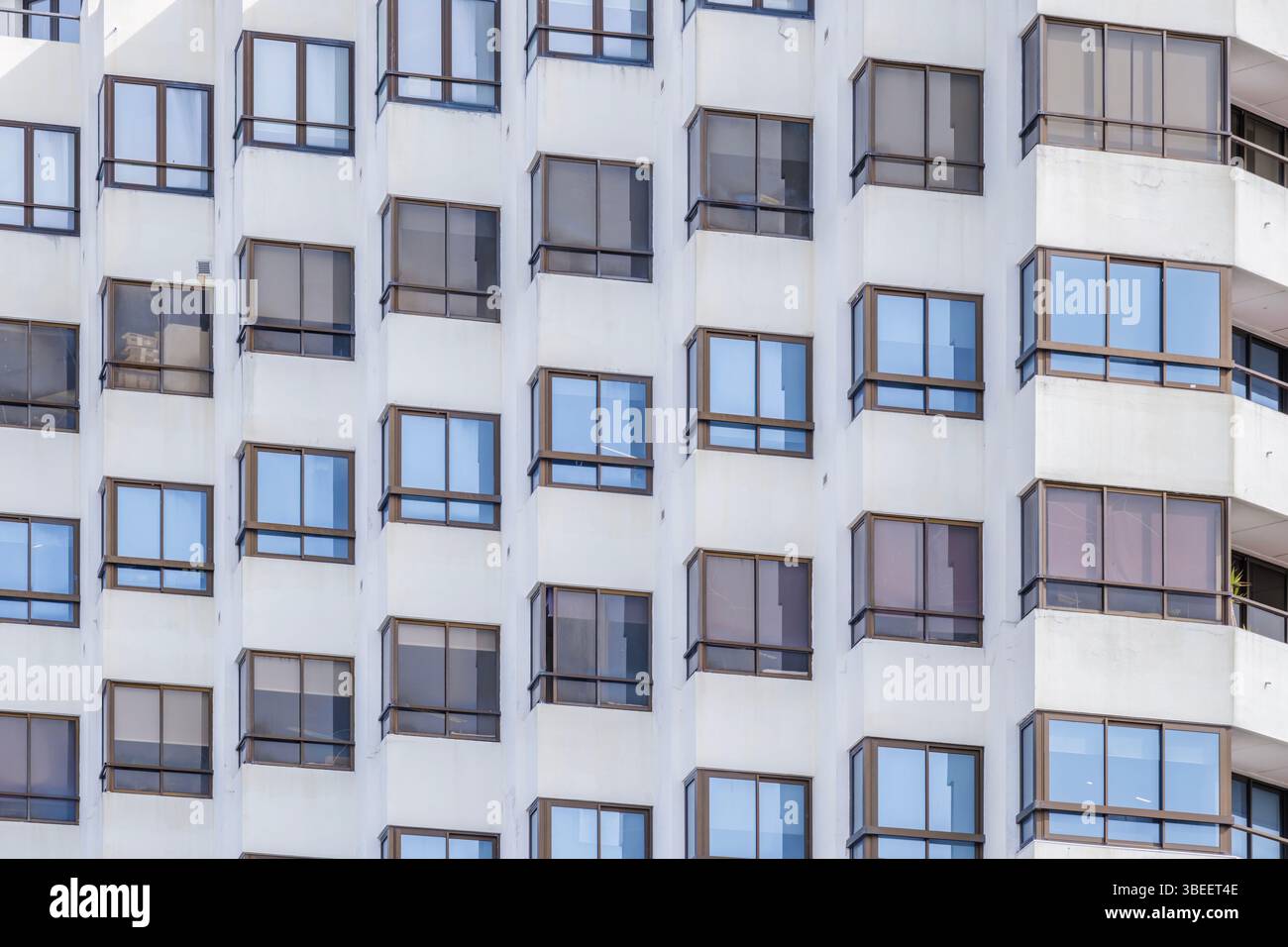 Façade moderne de bâtiment d'appartement blanc avec motif de fenêtre géométrique. Architecture résidentielle contemporaine, balcons en verre, urbanisme développeurs Banque D'Images