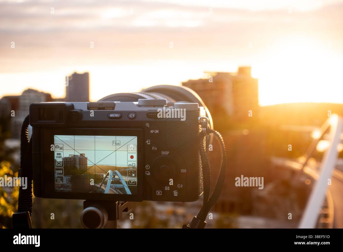 Photographie professionnelle avec un appareil photo sur un trépied photographiant un paysage urbain contre le soleil au coucher du soleil pour un concept de passe-temps Banque D'Images