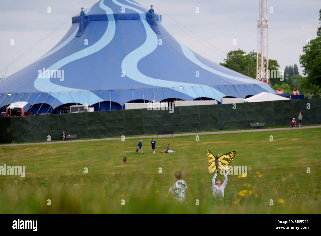 Les utilisateurs du parc font voler un cerf-volant papillon dans un champ qui surplombe l'une des grandes chapelles du festival Wide Awake à Brockwell Park à Herne Hill, Lambeth, le 19 mai 2025, dans le sud de Londres, en Angleterre. Les militants locaux ont traduit le conseil de Lambeth devant la haute Cour afin de mettre fin aux événements estivaux de Brockwell Park qui, selon eux, n'avaient pas le permis de construire correct. Après que les militants eurent initialement gagné leur cause, Lambeth a ensuite fait appel et Wide Awake a continué avec plus d'événements musicaux live cet été, y compris Mighty Hoopla, qui devraient attirer des centaines de milliers de personnes. Le pr Banque D'Images