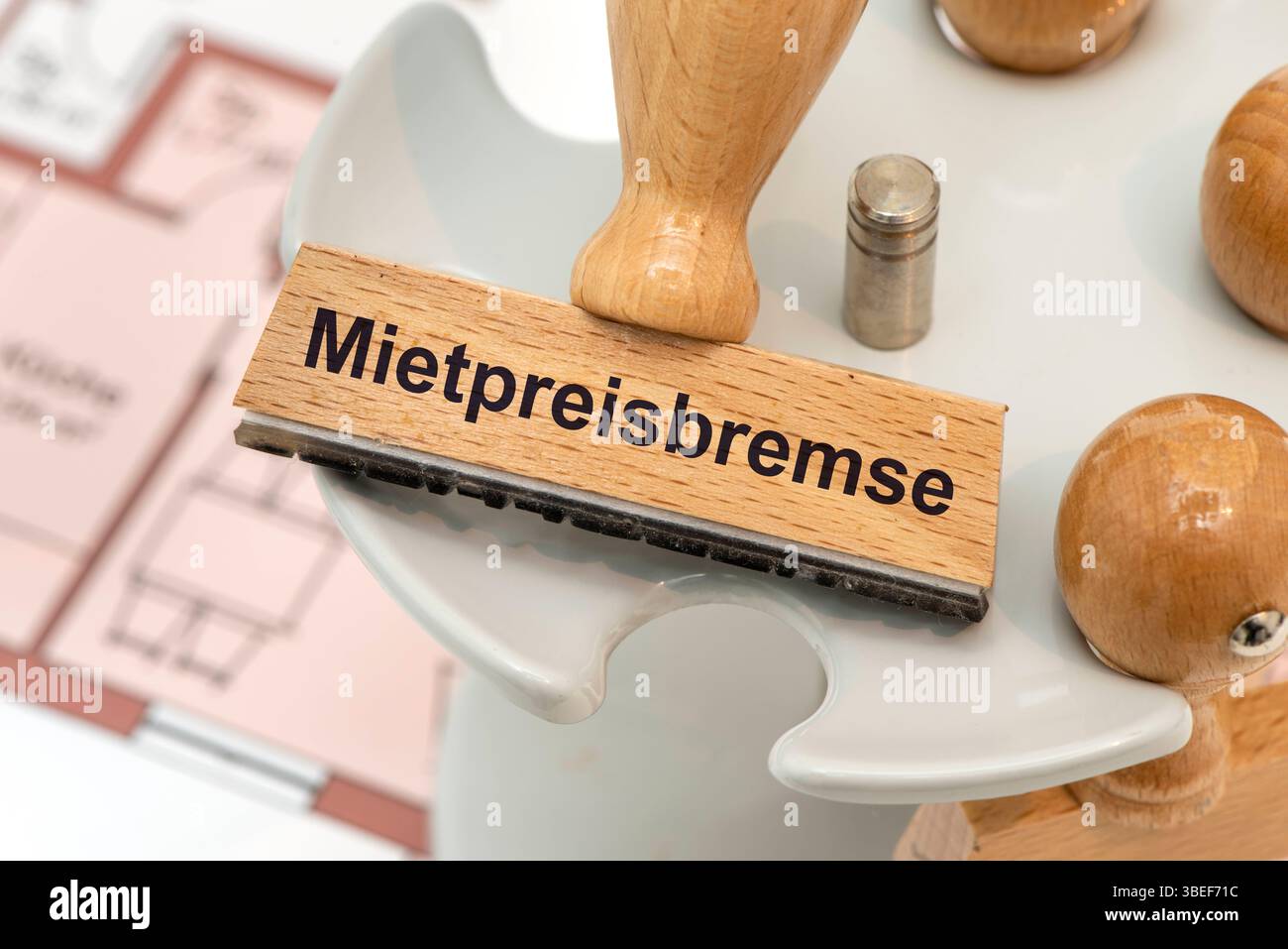 Mietpreisbremse gegen Mieterhöhung Ein Holzstempel ist beschriftet mit Mietpreisbremse über einem Grundriss einer Mietwohnung *** contrôle des loyers contre Banque D'Images