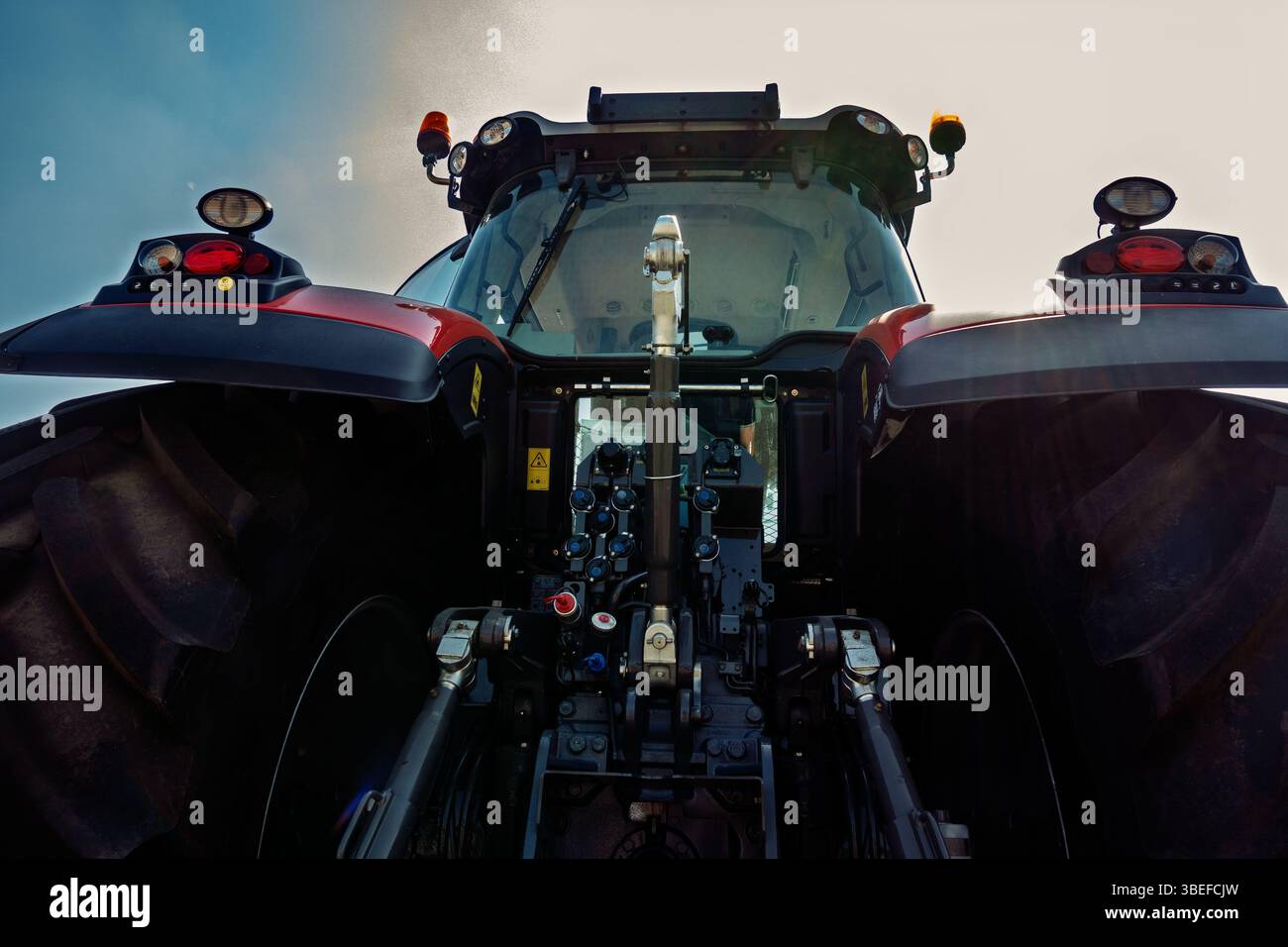 L'arrière du tracteur moderne avec de grandes roues dans le champ contre le ciel bleu. Banque D'Images
