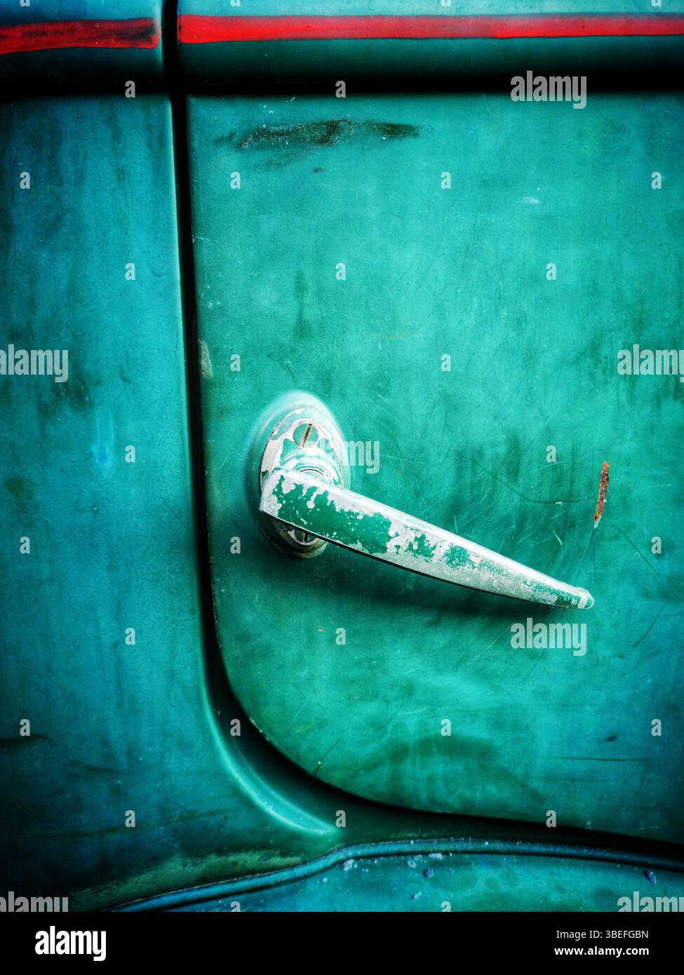 Une vue rapprochée d'une poignée de porte de voiture d'époque avec une surface altérée et une peinture vert éclatant. Banque D'Images