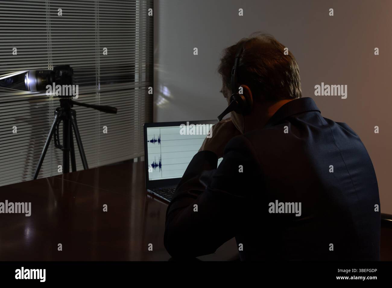Un agent infiltré travaille la nuit : caméra, écouteurs, enregistrement audio sur un écran d'ordinateur portable Banque D'Images