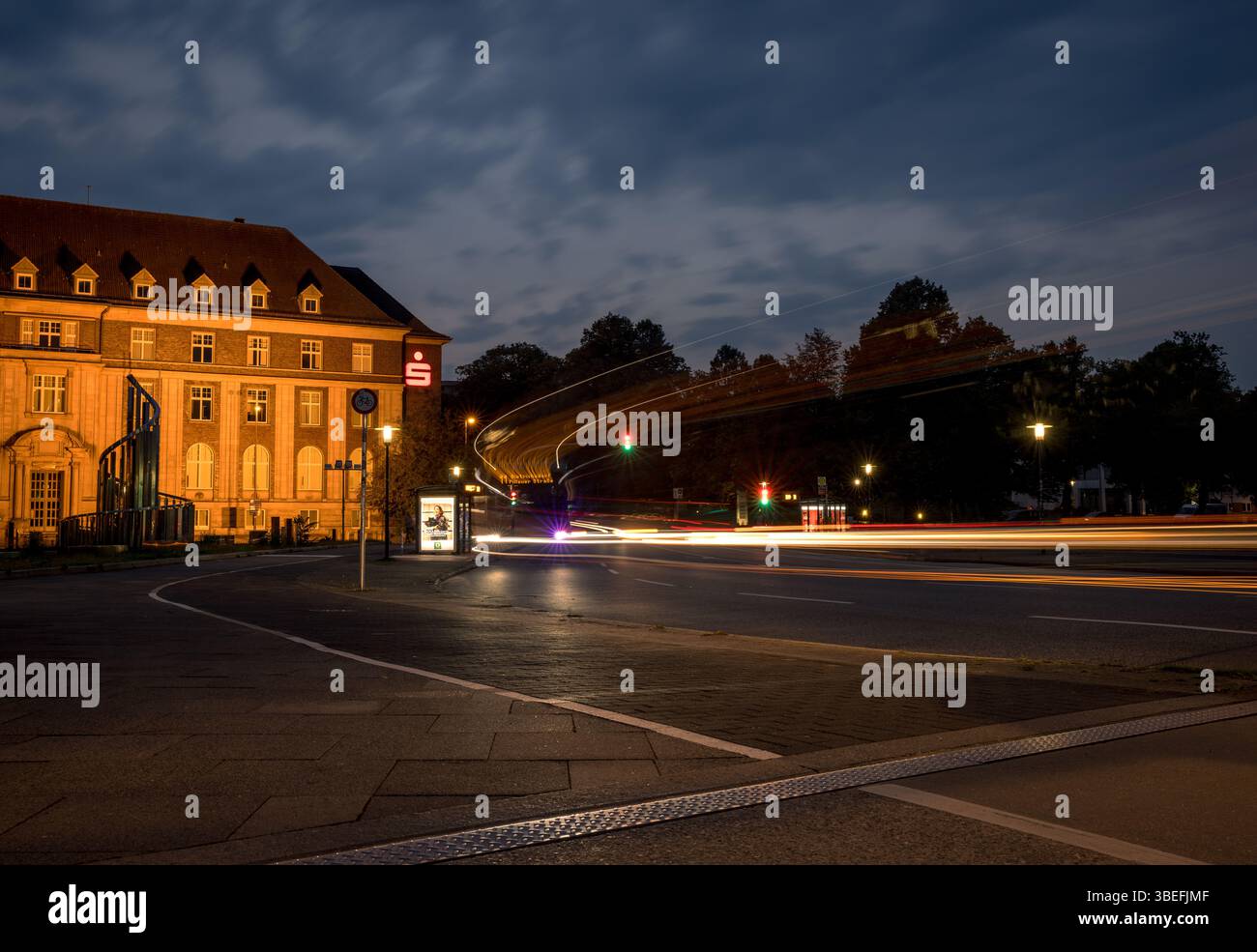 Image longue exposition du bâtiment de la banque Sparkasse et de la circulation routière à Kiel, en Allemagne, avec des traînées lumineuses illuminées et le ciel nocturne. Éditorial uniquement. Banque D'Images