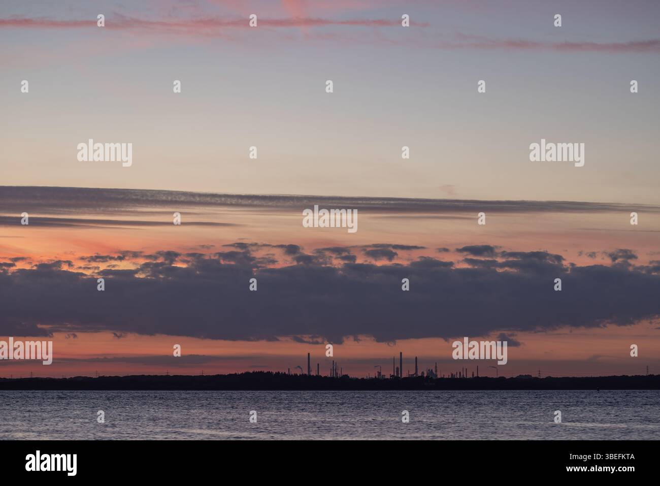 Complexe de raffinerie industrielle silhouette au coucher du soleil, vue sur Southampton Water depuis l'île de Wight, au Royaume-Uni. Crépuscule atmosphérique et sombre. Banque D'Images Complexe de raffinerie industrielle silhouette au coucher du soleil, vue sur Southampton Water depuis l'île de Wight, au Royaume-Uni. Crépuscule atmosphérique et sombre. Banque D'Images