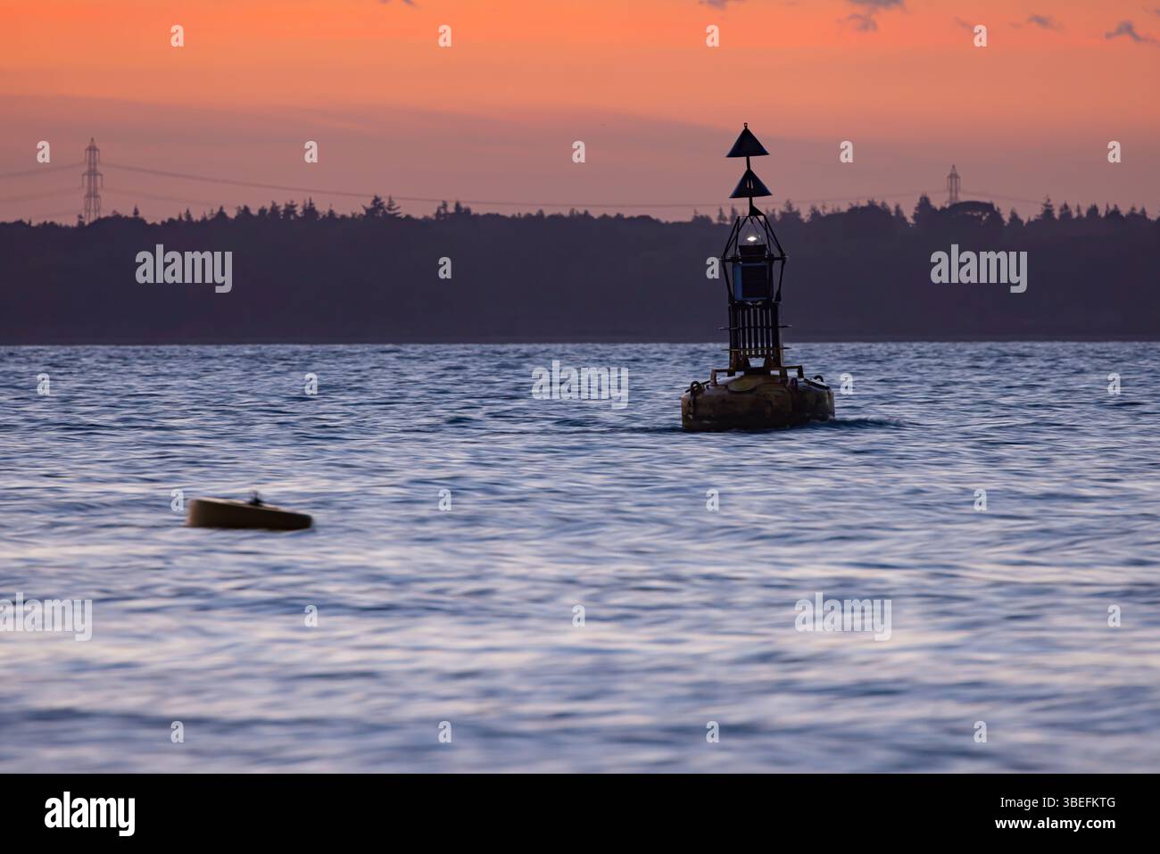 Bouée de navigation silhouette contre un ciel crépusculaire éclatant au large de l'île de Wight, au Royaume-Uni. Infrastructures maritimes sur les eaux côtières au coucher du soleil. Banque D'Images Bouée de navigation silhouette contre un ciel crépusculaire éclatant au large de l'île de Wight, au Royaume-Uni. Infrastructures maritimes sur les eaux côtières au coucher du soleil. Banque D'Images