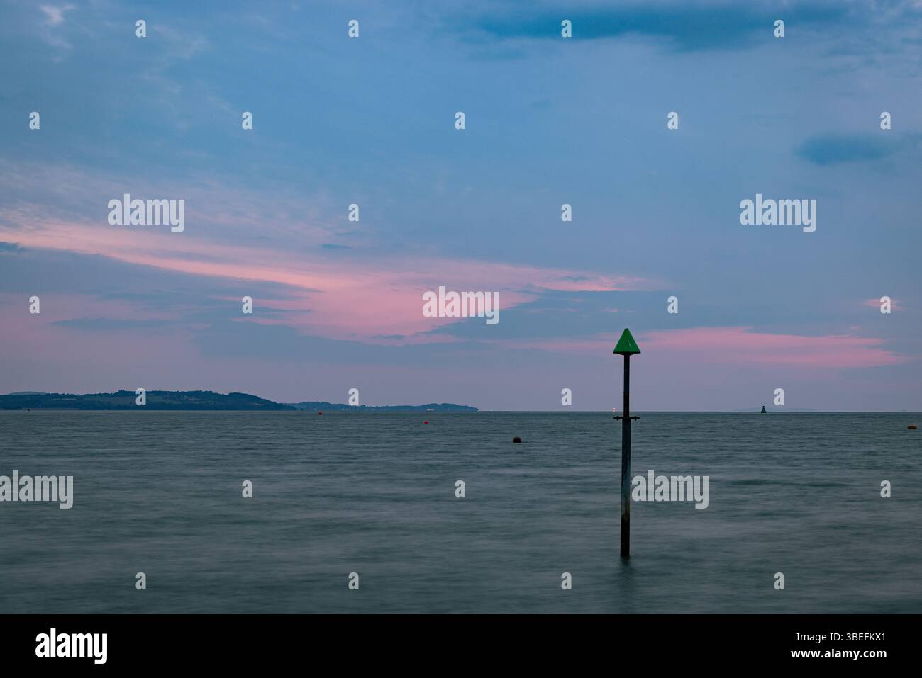 Pôle de navigation vert dans la mer calme pendant le crépuscule avec le ciel pastel, île de Wight, Royaume-Uni. Symbole de la sécurité maritime et de la navigation côtière. Banque D'Images Pôle de navigation vert dans la mer calme pendant le crépuscule avec le ciel pastel, île de Wight, Royaume-Uni. Symbole de la sécurité maritime et de la navigation côtière. Banque D'Images