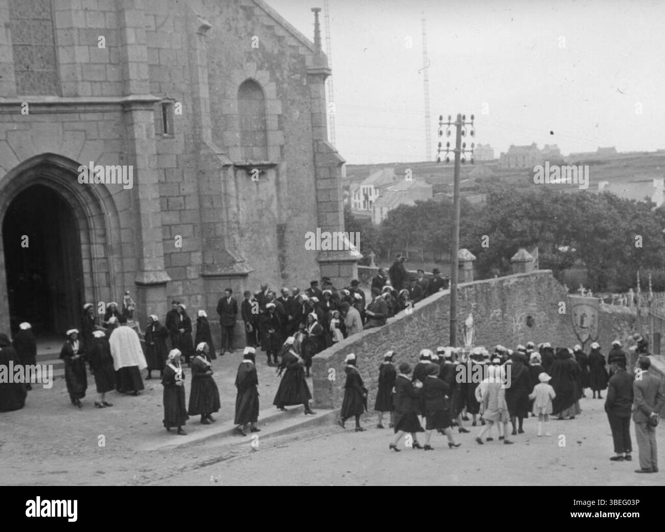 Cette photographie de 1910, prise par le Touring-Club de France, capture la procession du 15 août à Ouessant, une île au large des côtes bretonnes. L'image montre l'événement religieux local, mettant en évidence les traditions culturelles et religieuses de l'île. Banque D'Images
