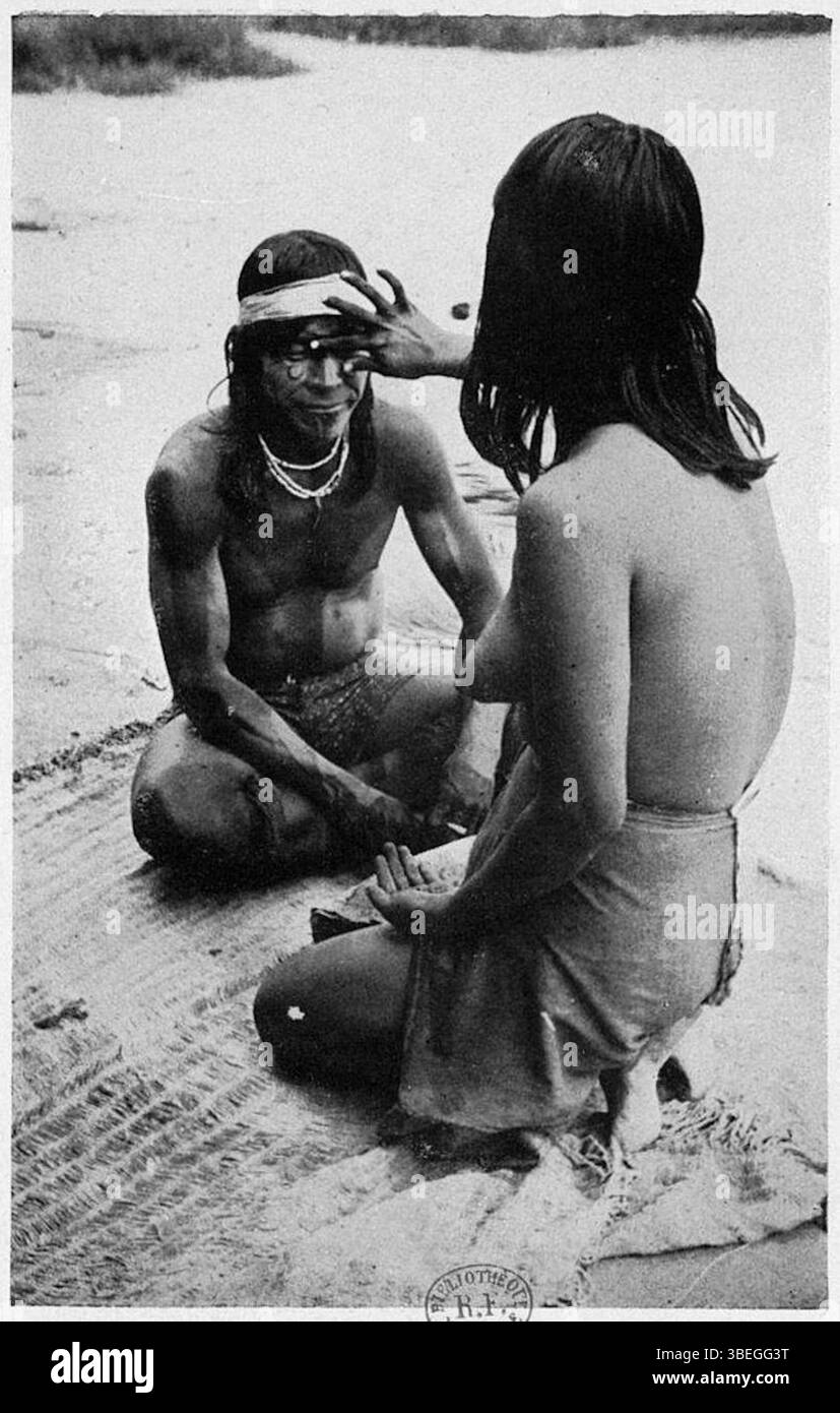Cette photographie de 1950 dans *aventures au Matto Grosso* montre une femme Javahé peignant son mari pour la cérémonie d’Aruana, illustrant les traditions artistiques indigènes en Amazonie brésilienne. Banque D'Images