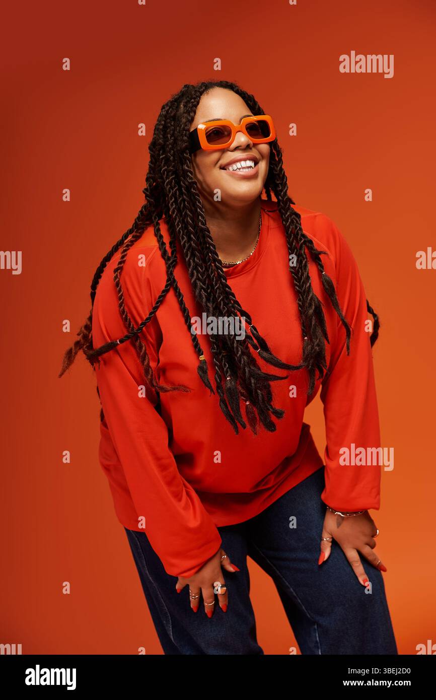 Une jolie femme afro-américaine avec des tresses met en valeur ses lunettes de soleil brillantes Banque D'Images