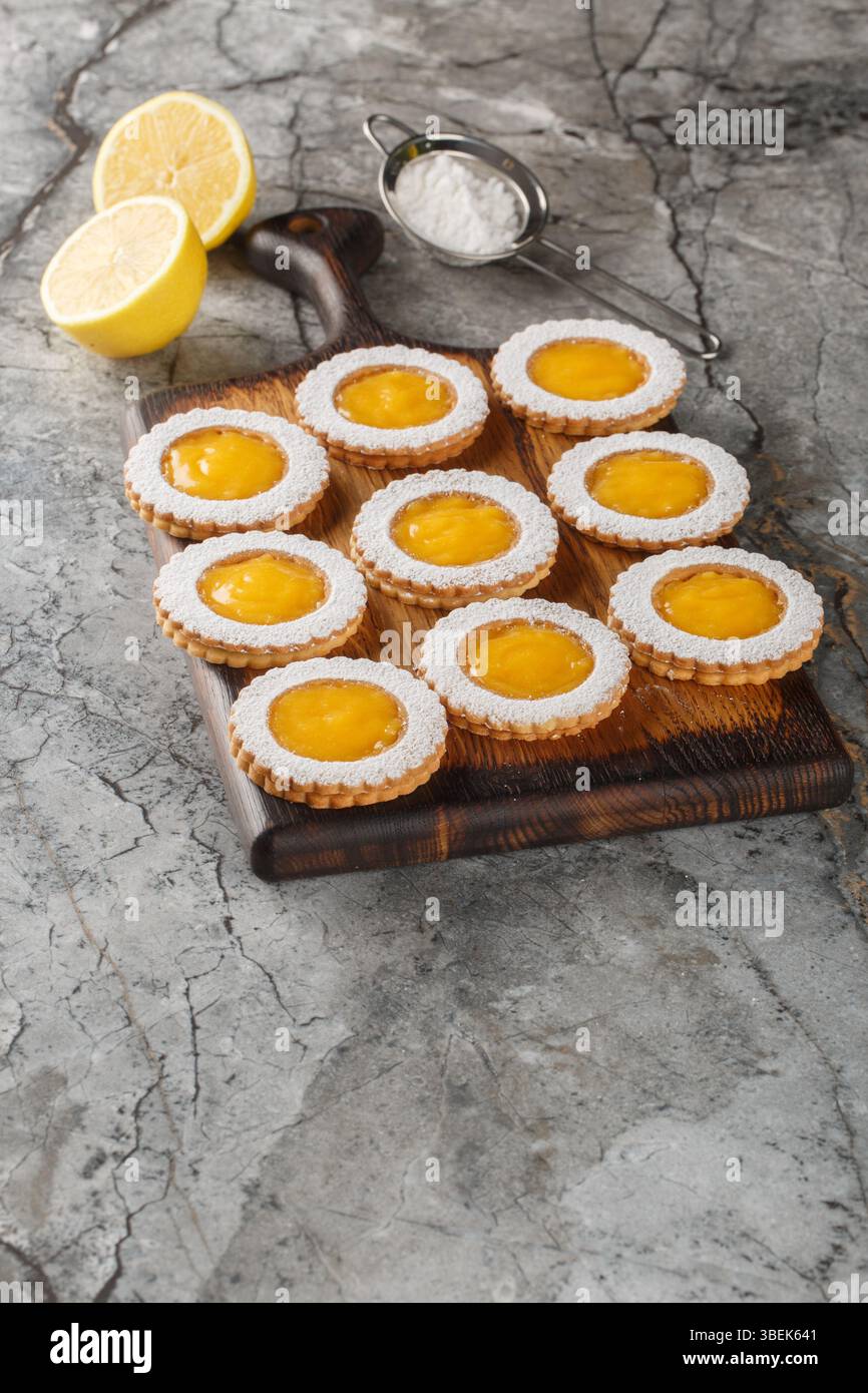 Les cookies combinent deux couches de biscuits Shortbread au beurre et un gros plan de remplissage de citron acidulé fait maison sur une planche de bois sur la table. Vertical Banque D'Images