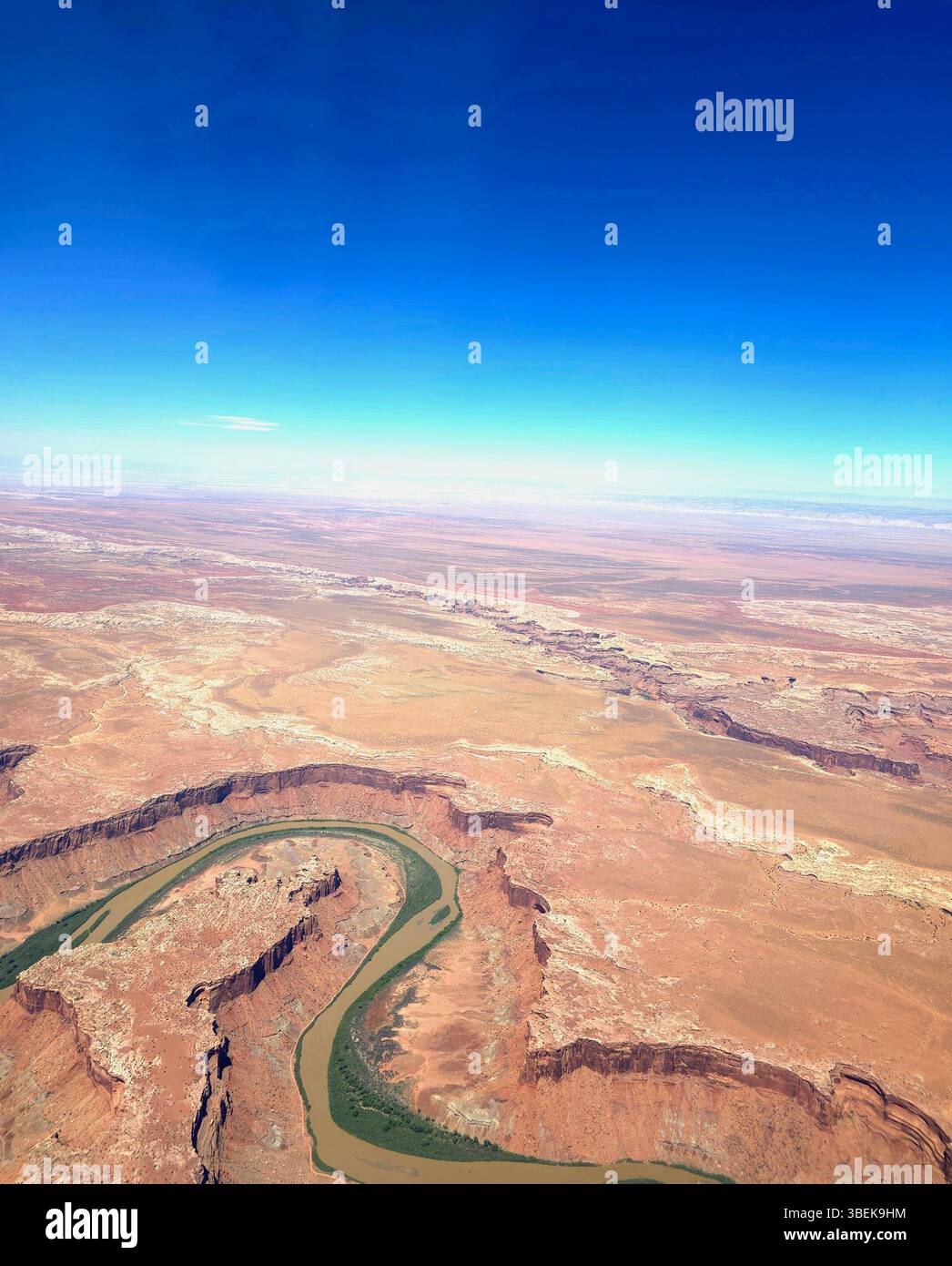 Rivière sinueuse coupant à travers les canyons du désert de roche rouge dans le sud-ouest américain, vue d'en haut sous un ciel bleu clair. - Image de stock capturée avec un smartphone