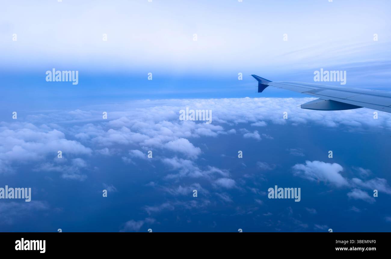 Avion volant au-dessus des nuages, vue aérienne de la fenêtre de l'avion, paysage nuageux moelleux et fond de ciel bleu Banque D'Images