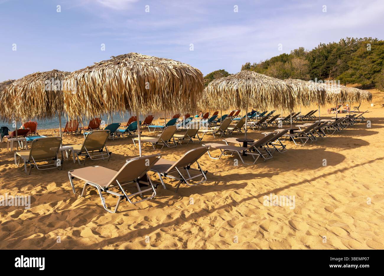 Parasols en paille et chaises longues sur le sable, journée ensoleillée en mer. Vacances d'été en Grèce Banque D'Images