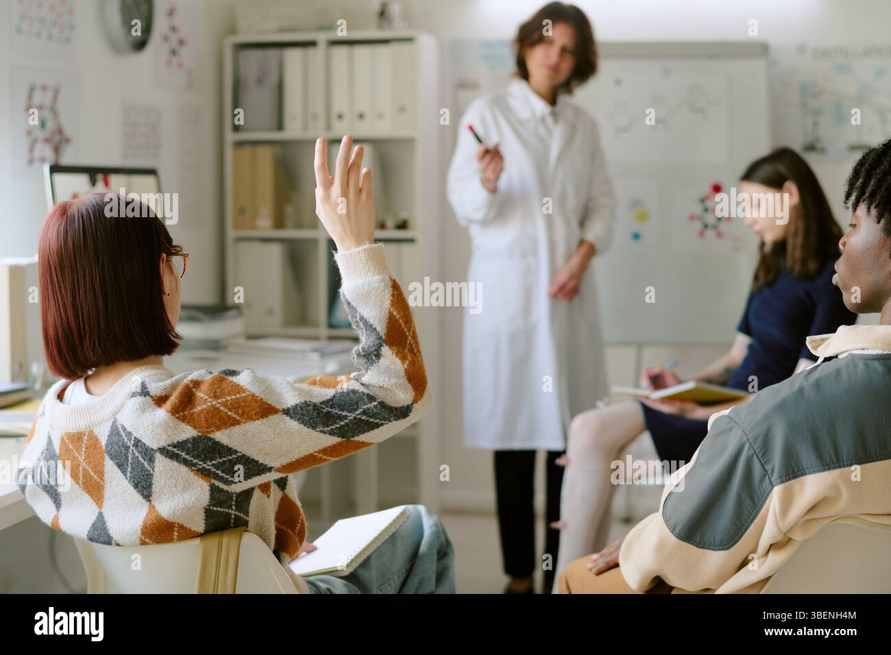 Élèves s'engageant dans une leçon interactive avec un enseignant tenant un marqueur dans le cadre de la classe. Divers matériels pédagogiques et dispositifs visibles en backgro Banque D'Images