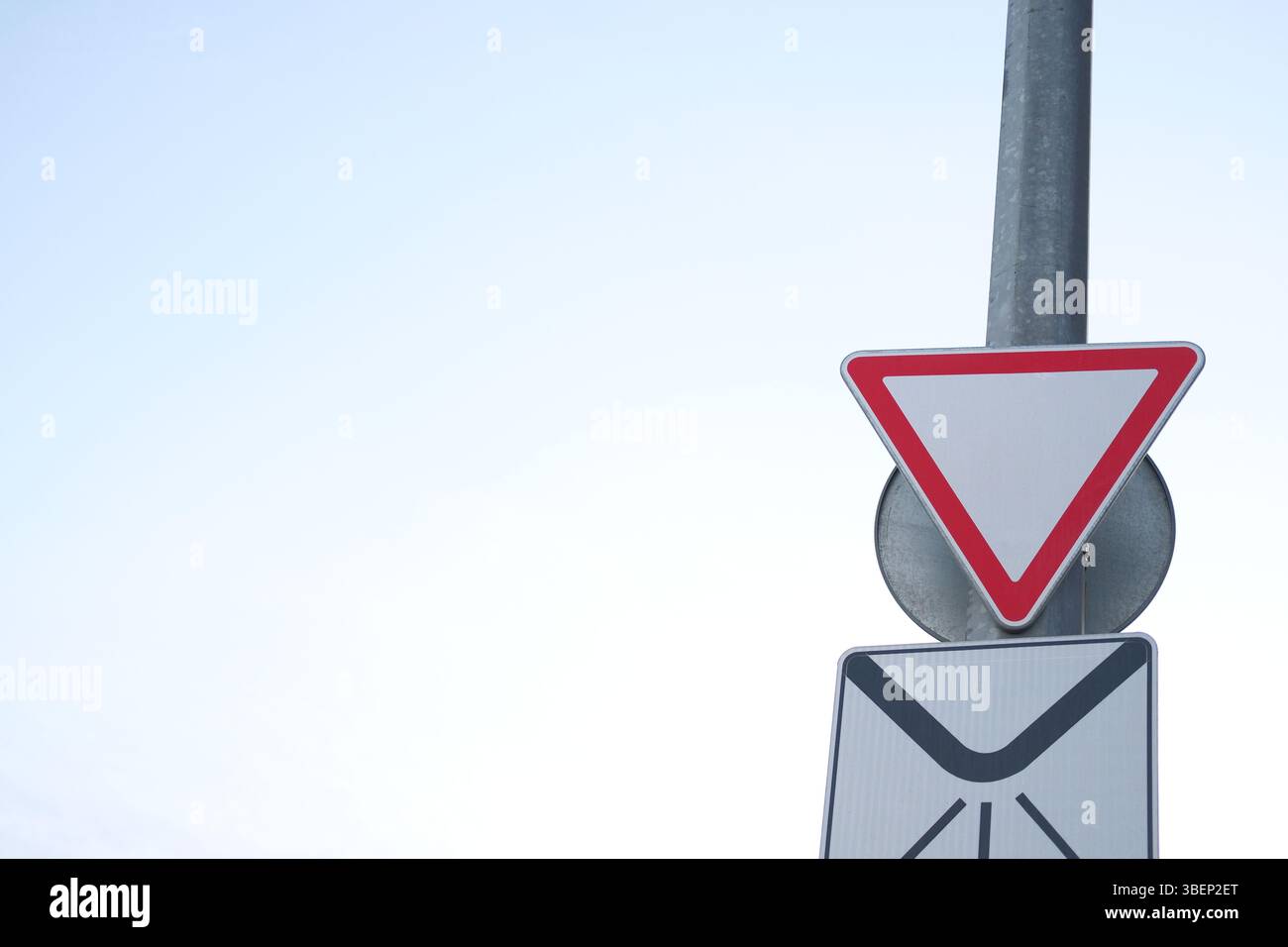 Panneau de signalisation routier indiquant le rendement prioritaire. L'arrière-plan est bleu pâle ciel. Concept de sécurité routière, espace de copie Banque D'Images