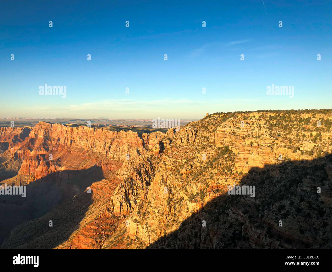 Vue à l'heure d'or de Desert View point et Watchtower au Grand Canyon avec une lumière chaude illuminant les falaises et les ombres profondes du canyon. - Image de stock capturée avec un smartphone