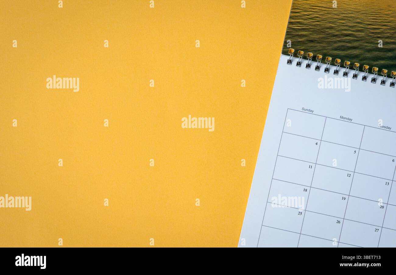Page de calendrier sur fond de table jaune. Vue de dessus, espace de copie. Banque D'Images
