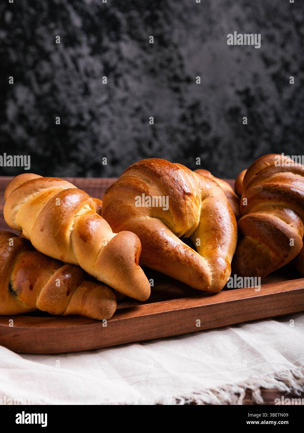 Un gros plan de plusieurs croissants fraîchement cuits disposés sur un plateau en bois rustique. Banque D'Images