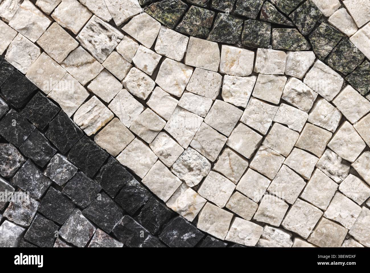 Image détaillée montrant une mosaïque de pierre texturée avec des carreaux neutres et noirs contrastés, mettant en valeur l'artisanat et le design artistique, idéal pour inter Banque D'Images