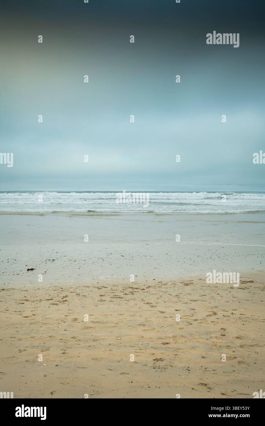 Figure d'un surfeur solitaire chevauchant une vague à Fistral Beach lors d'un Noël frais et brumeux à Newquay en Cornouailles au Royaume-Uni. Banque D'Images