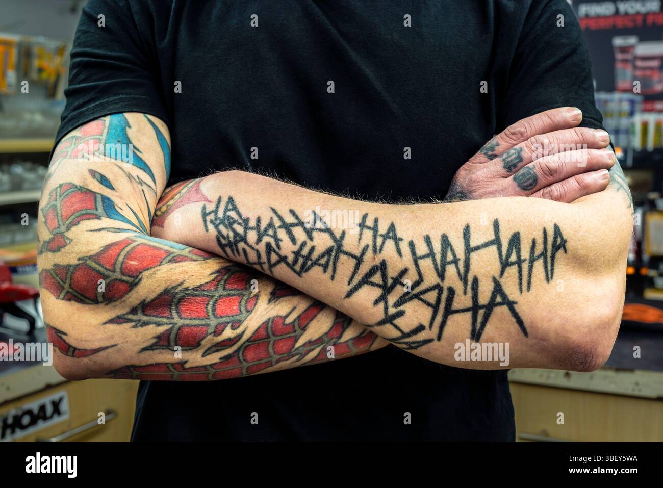 Un homme homme homme avec tatouage tatoué bras plié au Royaume-Uni. Banque D'Images