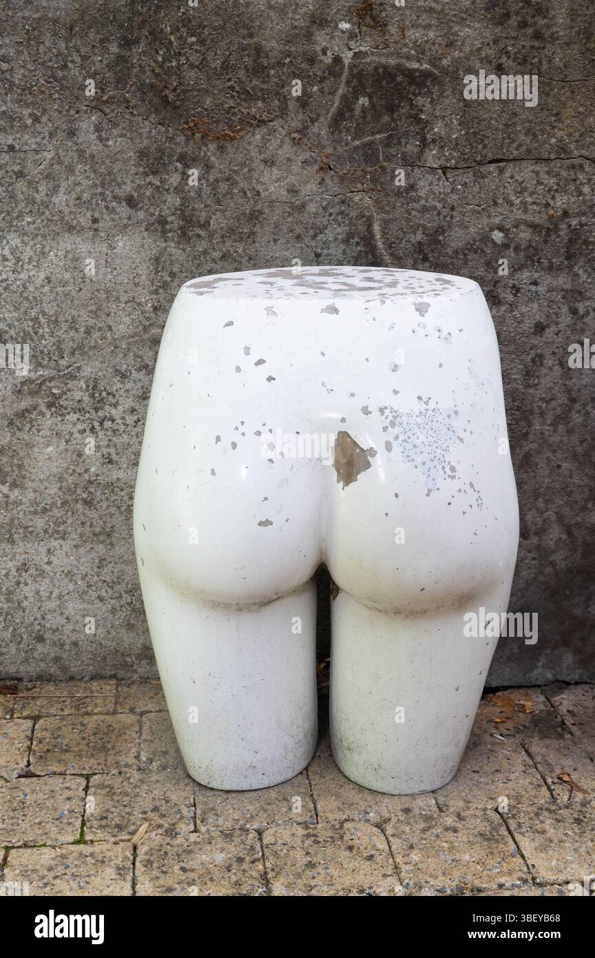 Un seul vieux mannequin de moitié inférieure se tient contre un mur de béton rugueux Banque D'Images