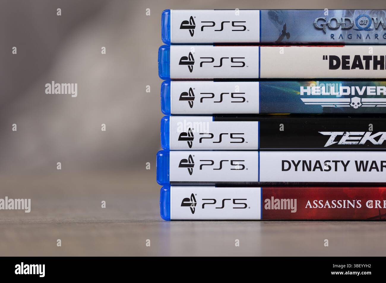 Brecht, Belgique - 18 avril 2025 : une pile de plusieurs étuis ou boîtes de jeux vidéo sony playstation 5 reposant sur une table en bois. Prêt à jouer à un jeu sur console Banque D'Images