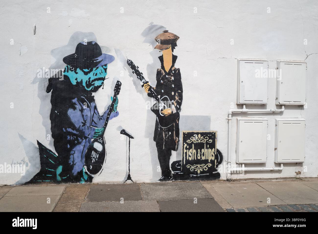 Fish and Chips, graffiti de poissons jouant en groupe habillé de chapeaux et manteaux Banque D'Images