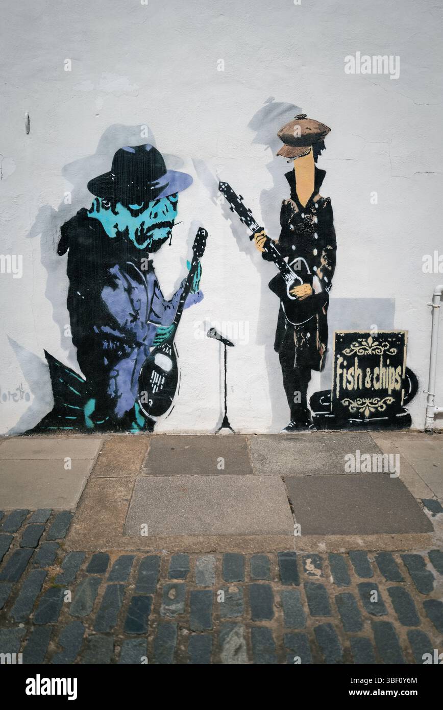 Fish and Chips, graffiti de poissons jouant en groupe habillé de chapeaux et manteaux Banque D'Images
