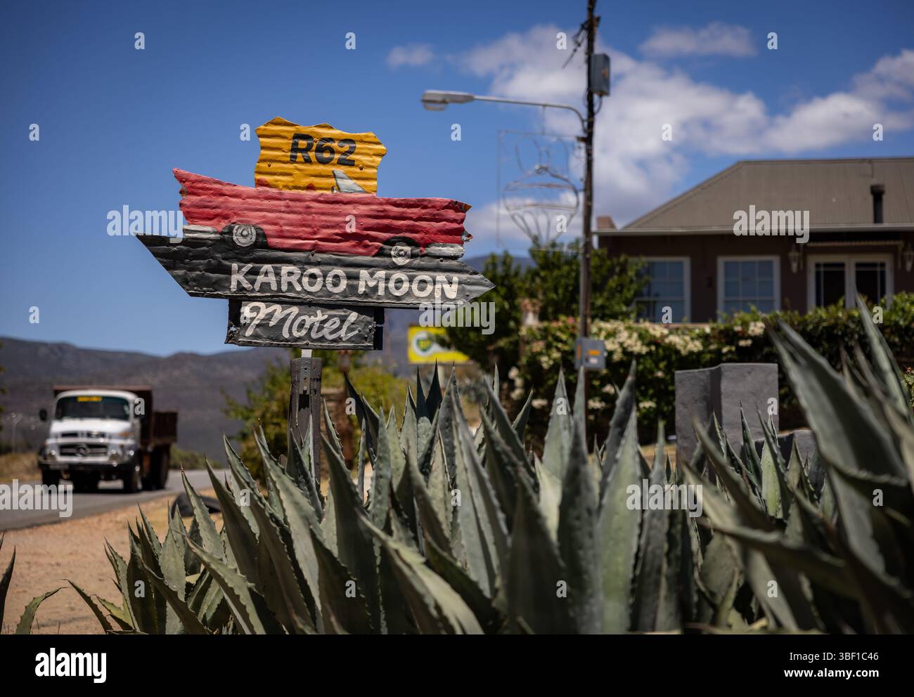 Panneau peint au bord de la route pour le Karoo Moon Motel sur la route 62 en Afrique du Sud, avec des usines d'agave et un camion qui passe à l'arrière-plan. Banque D'Images
