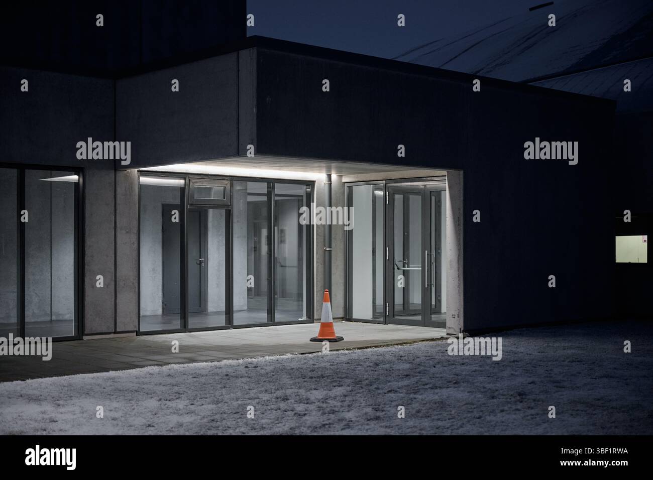 Entrée du bâtiment moderne avec cône de circulation la nuit pendant l'hiver Banque D'Images