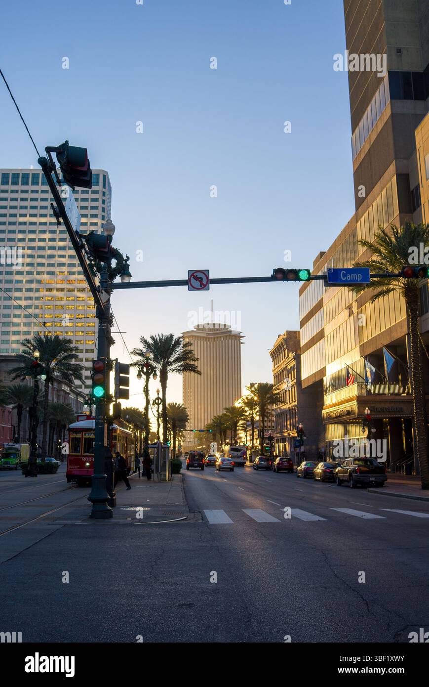 Une scène de rue de la Nouvelle-Orléans au coucher du soleil. Des voitures et un tramway se déplacent le long de Camp Street. Banque D'Images