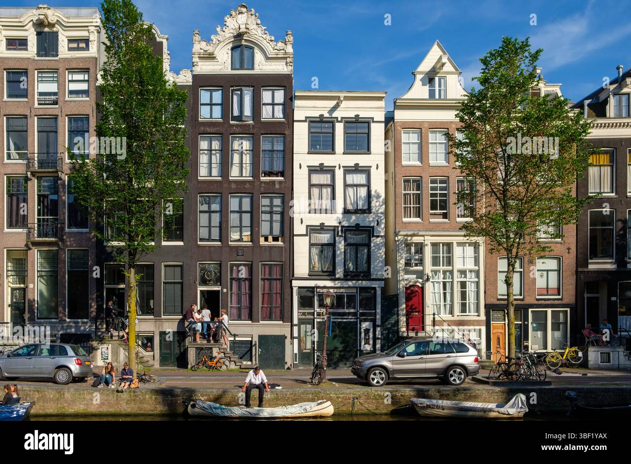 Scène du canal d'Amsterdam : les gens se détendent au bord de l'eau, en profitant du soleil et de la vue sur les maisons historiques du canal. Banque D'Images