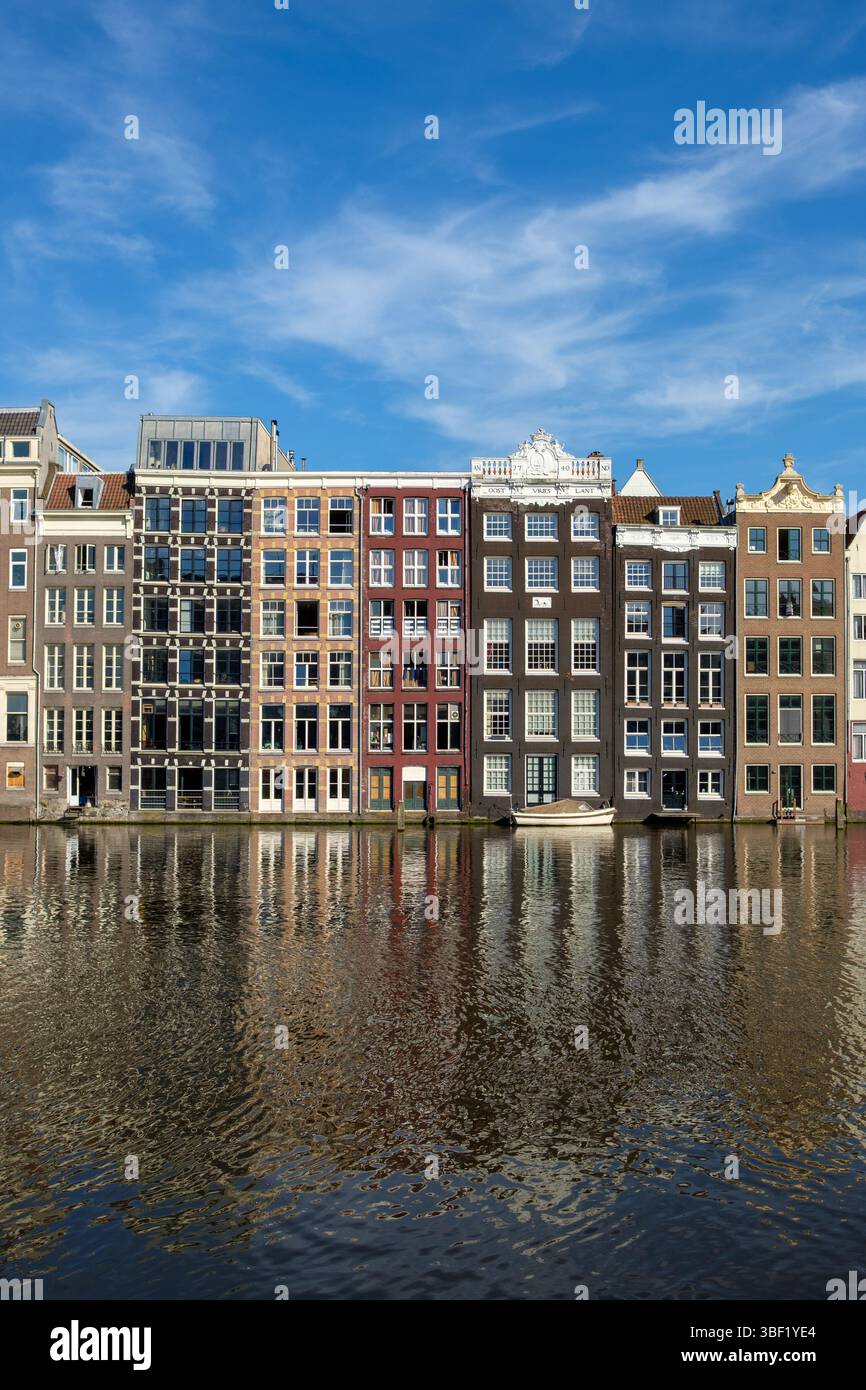 Les maisons de canal d'Amsterdam se reflètent dans l'eau par une journée ensoleillée. Les touristes visitent pour voir l'architecture. Banque D'Images