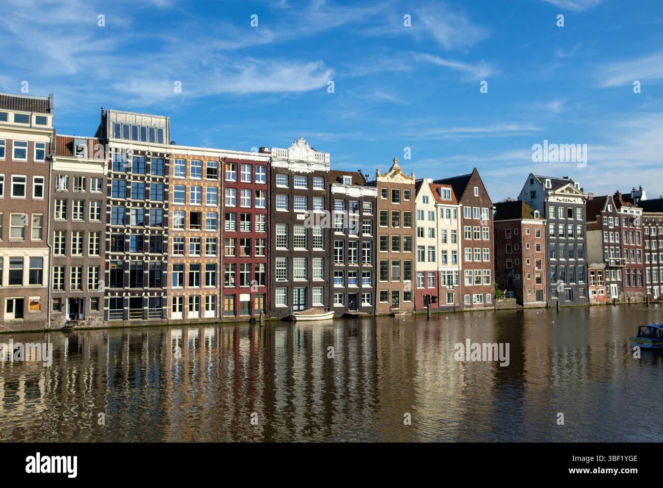 Les maisons de canal d'Amsterdam se reflètent dans l'eau. Les touristes apprécient la vue et l'histoire. Banque D'Images