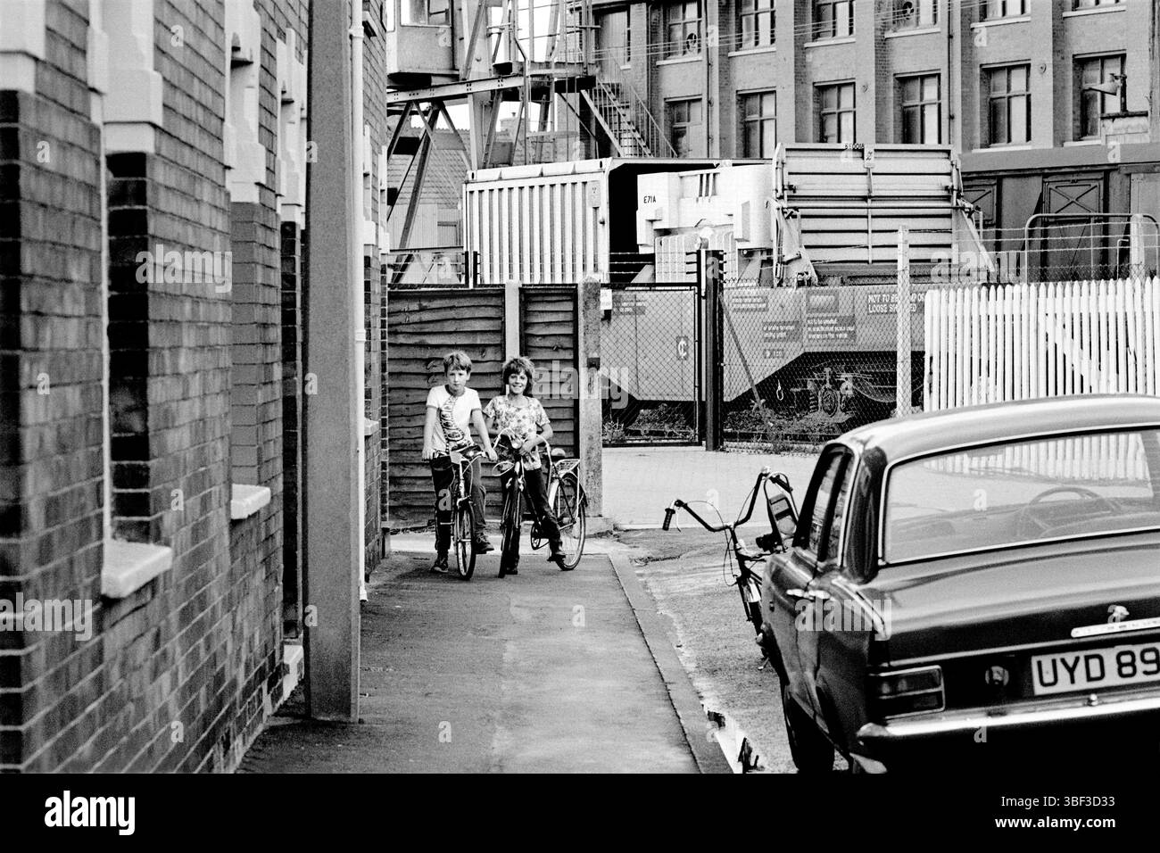 Des enfants de Bailey Street, Bridgwater, Somerset, avec une fiole de combustible nucléaire irradié derrière. La fiole, remplie de combustible hautement radioactif provenant de la centrale nucléaire de Hinkley point B, est en préparation pour son voyage vers Sellafield. La tête de chemin de fer où les flacons sont chargés et déchargés est proche de la gare et des maisons locales. Banque D'Images