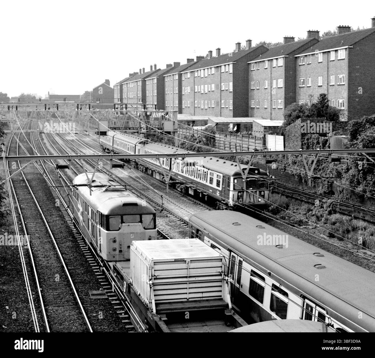 Un train à flasques nucléaires passe devant des trains de voyageurs dans l'est de Londres près de la gare d'Ilford. Banque D'Images