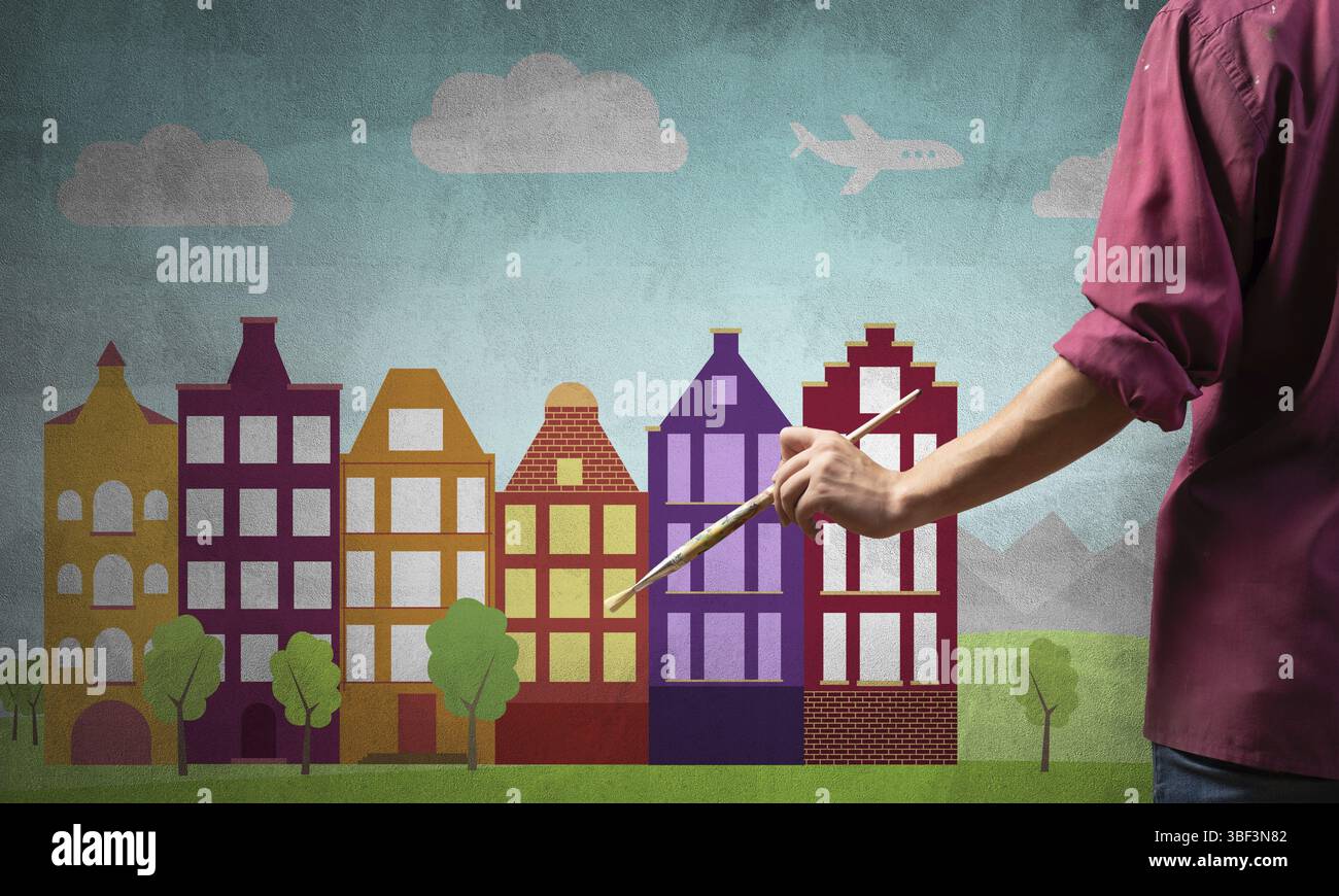 Gros plan main d'artiste tenant le pinceau. Peintre en chemise debout sur fond image colorée de la ville. Paysage urbain d'été avec de hauts bâtiments artwor Banque D'Images