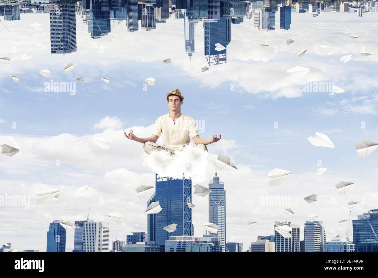 Jeune homme gardant les yeux fermés et regardant concentré tout en méditant sur les nuages parmi les avions de papier volants et entre deux mondes Banque D'Images